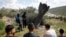 People gather around remnants of a missile stuck in the ground found in Kifl Haris village, near Nablus in the Israeli-occupied West Bank, on March 24.