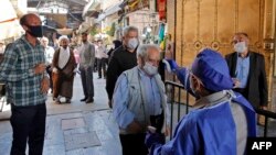 An Iranian official checks the temperature of visitors at the Shah Abdol-Azim shrine in the capital Tehran, May 25, 2020