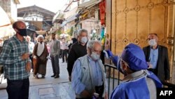 An Iranian official checks the temperature of visitors at the Shah Abdol-Azim shrine in the capital Tehran, May 25, 2020