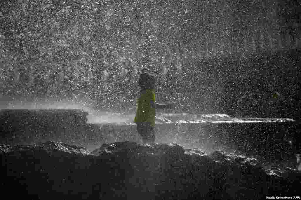 A child cools off in a fountain during a hot spring day in downtown Moscow. (AFP/Natalia Kolesnikova)