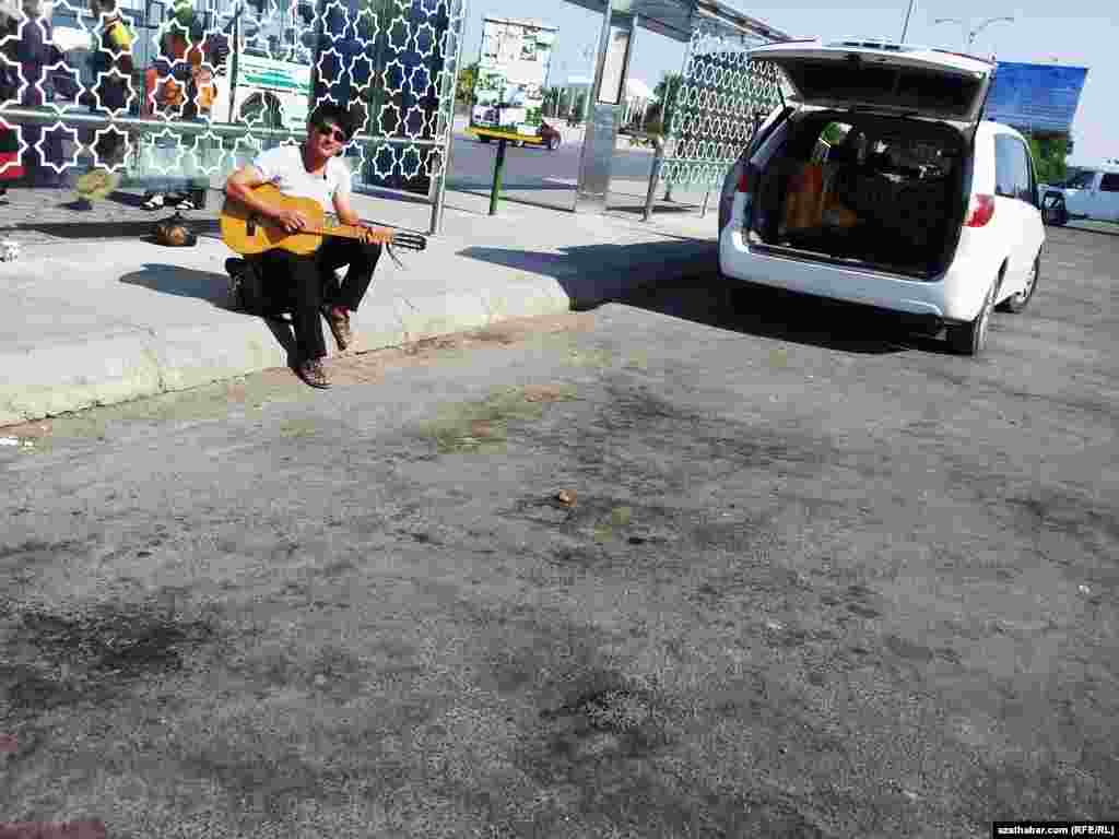 Türkmenabadyň wokzalynda gitara çalyp oturan oglan