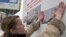 An activist sticks a poster of leading opposition candidate Alyaksandr Milinkevich onto a wall in Minsk