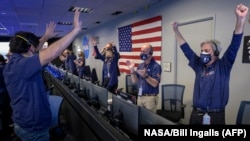 Ground controllers at NASA's’s Jet Propulsion Laboratory in Pasadena, California, throw their arms in the air and cheer after receiving confirmation that the Perseverance rover had touched down on Mars.