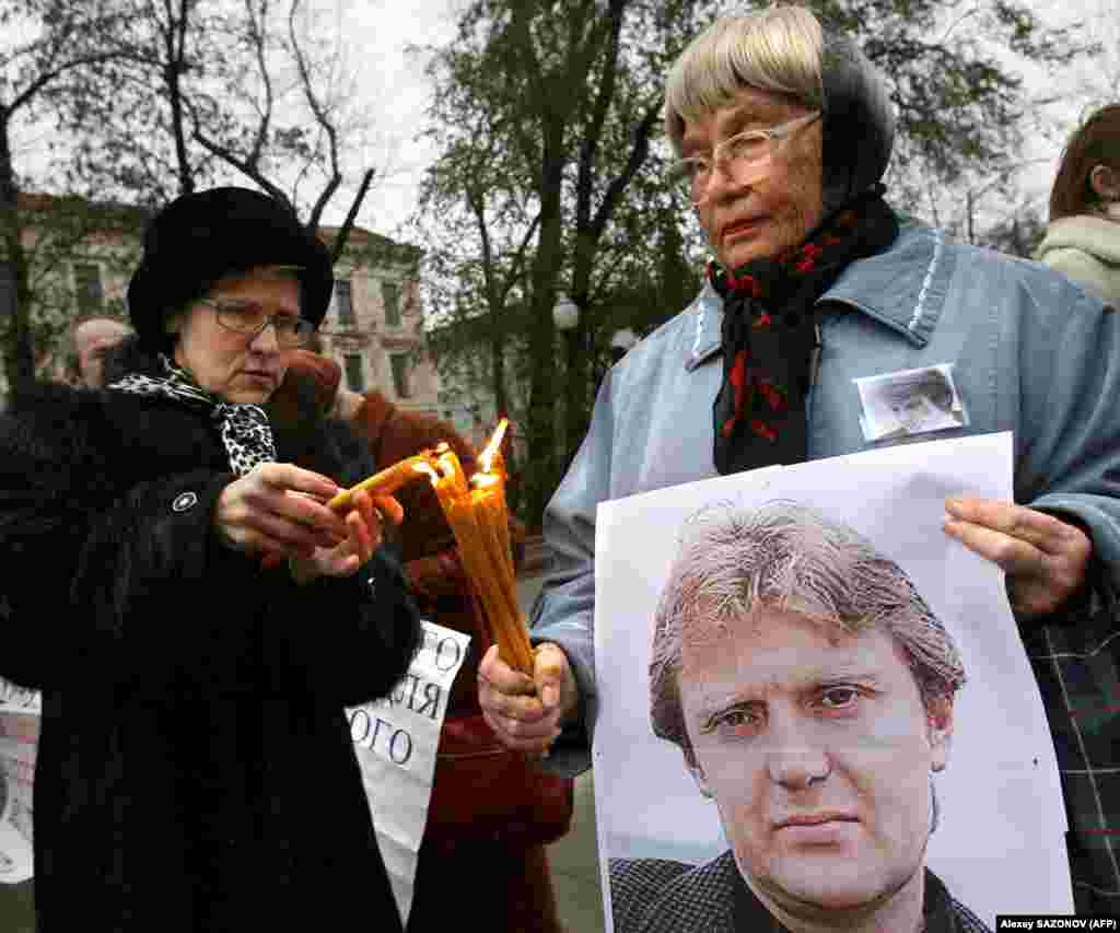 Жінки тримають плакат з портретом Литвиненка і запалюють свічки під час московського меморіалу за Олександром Литвиненком, 22 листопада 2008 року