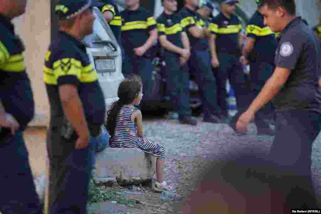 24 июля — девочка среди полицейских во время выселения жителей из дома на улице Твалчрелидзе в Тбилиси. Фото: Илиа Ратиани / Грузинская служба Радио Свобода.