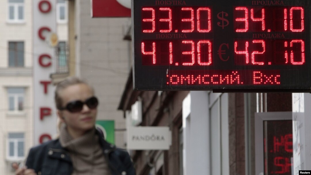 A woman passes by a sign displaying ruble exchange rates in Moscow. The Russian currency recently fell to its lowest level against the US. dollar in almost five years. (file photo)