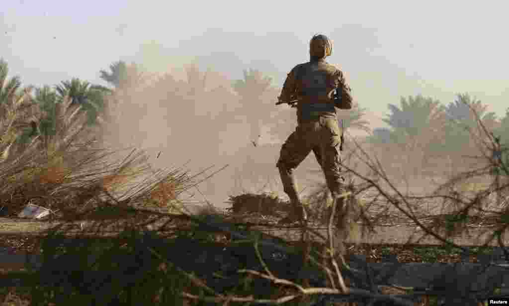 An Iraqi Shi'ite fighter fires his weapon during a battle with Islamic State militants at Al-Nibai, north of Baghdad. (Reuters)