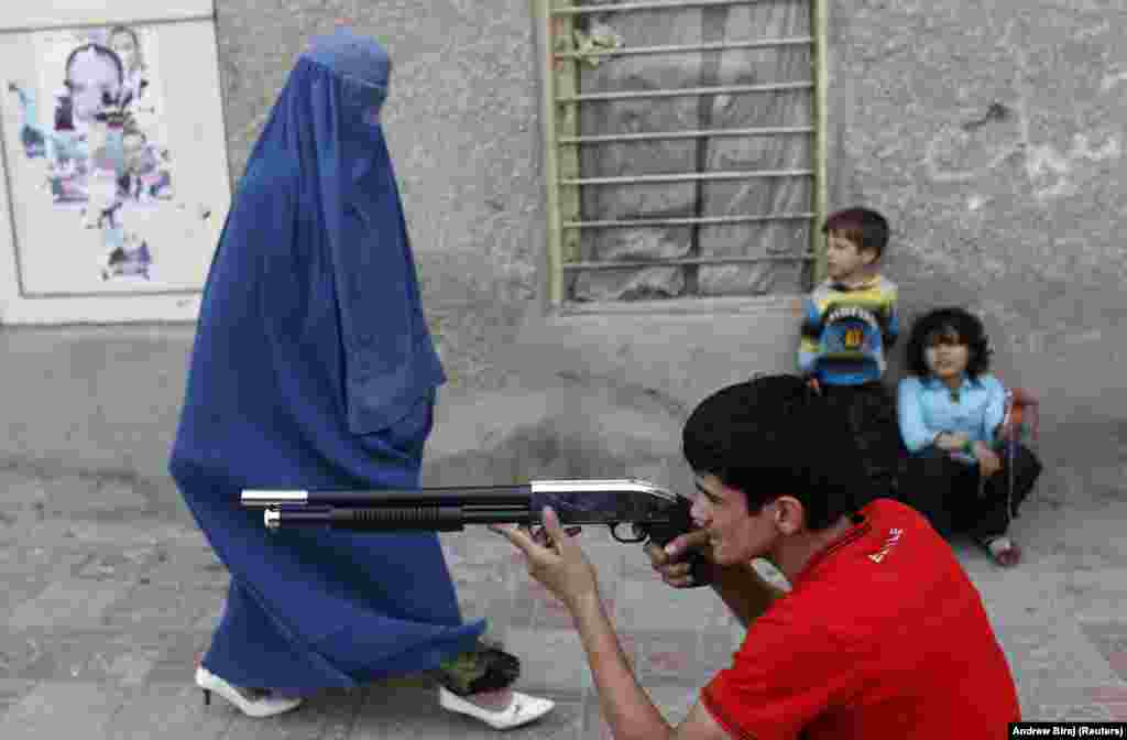 Një grua e veshur me burka, duke ecur para një djali me një pushkë lodër. (Kabul, 13 shtator 2010)