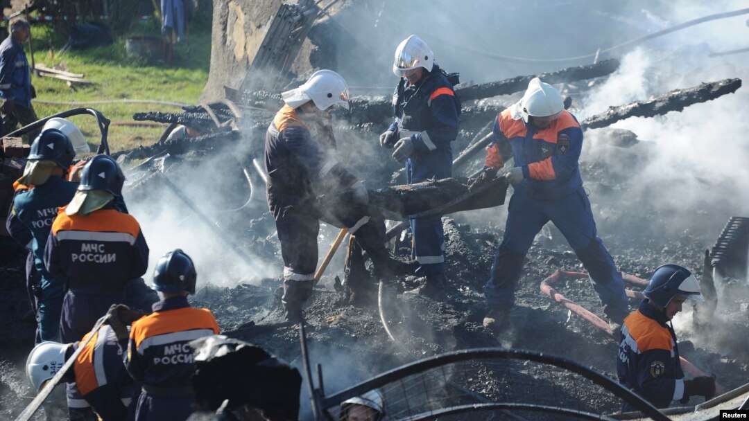 Russia -- Emergencies Ministry employees carry the burnt body of a victim from the debris of a psychiatric hospital destroyed by fire in the Novgorod region town of Luka, September 13, 2013