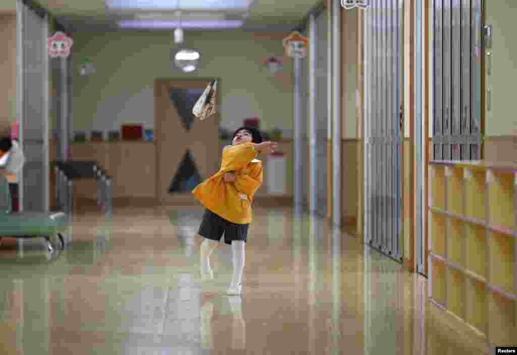 A boy plays with a paper plane in the corridor of a kindergarten in Koriyama.