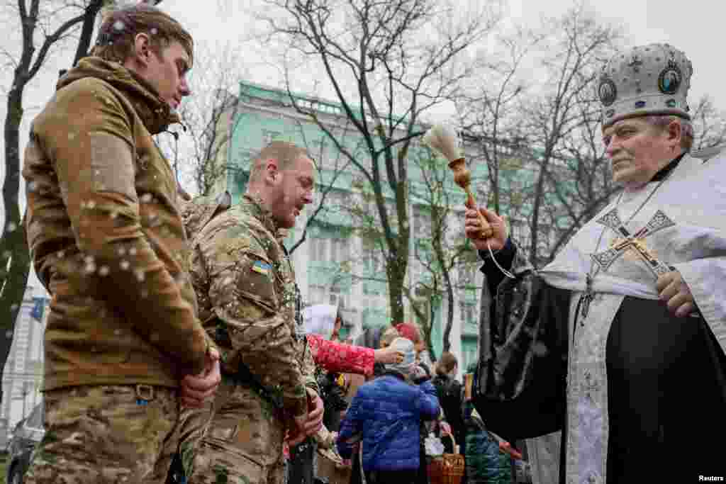 An Orthodox priest sprays holy water on soldiers during a service in Kyiv on April 16.
