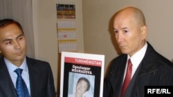 Annadurdy Hadjiev (right) holds a poster of his sister, RFE/RL correspondent Ogulsapar Muradova, who died while in Turkmen police custody, as a Turkmen diplomat looks on during the occupation of the Turkmen Embassy in Paris.