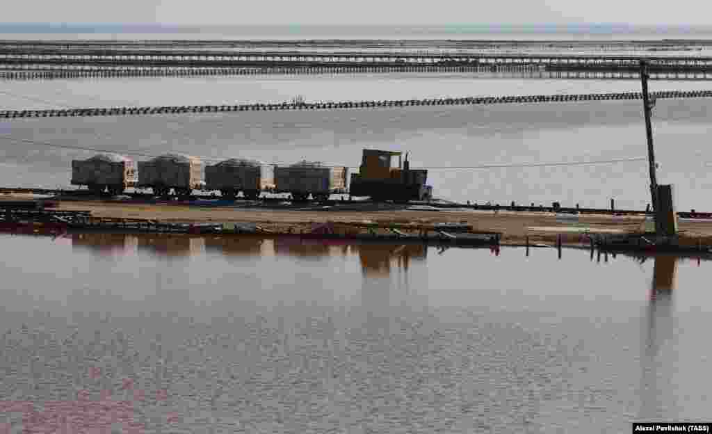 A miniature train carries salt along the shores of the lake.