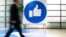 A Facebook alkalmazottja a „like” jelzés mellett sétál a Facebook központjában, Kaliforniában, 2019. október 23-án