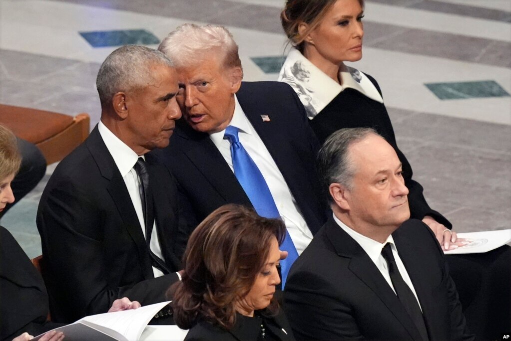 Ish-presidenti Barack Obama bisedon me presidentin e zgjedhur Donald Trump, derisa Melania Trump dëgjon, dhe, në të njëjtën kohë, nënpresidentja Kamala Harris dhe bashkëshorti i saj, Doug Emhoff, mbërrijnë, para funeralit shtetëror të ish-presidentit Jimmy Carter në Katedralen Kombëtare të Uashingtonit, 9 janar 2025.