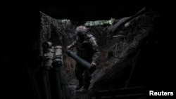 Артилерист 44-ї ОАБр ЗСУ несе снаряд, готуючись до стрільби з гаубиці M777, Дніпропетровська область, 24 грудня 2025 року