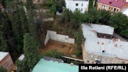ახალი მშენებლობის ადგილი ბარნოვის ქუჩის პირველ ჩიხში. საცხოვრებელ სახლს, ფოტოზე მარჯვნივ, 2007 წლიდან არქიტექტურული ძეგლის სტატუსი აქვს და ავარიულია. ავარიულია მშენებლობის წინ მდგარი ცისფერსახურავიანი შენობა.. ფოტო: 19 სექტემბერი, 2025