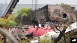 O echipă se pregătește să îndepărteze bucăți din avionul Air India, care s-a prăbușit joi, de pe acoperișul unei clădiri din Ahmedabad, India, sâmbătă, 14 iunie 2025.