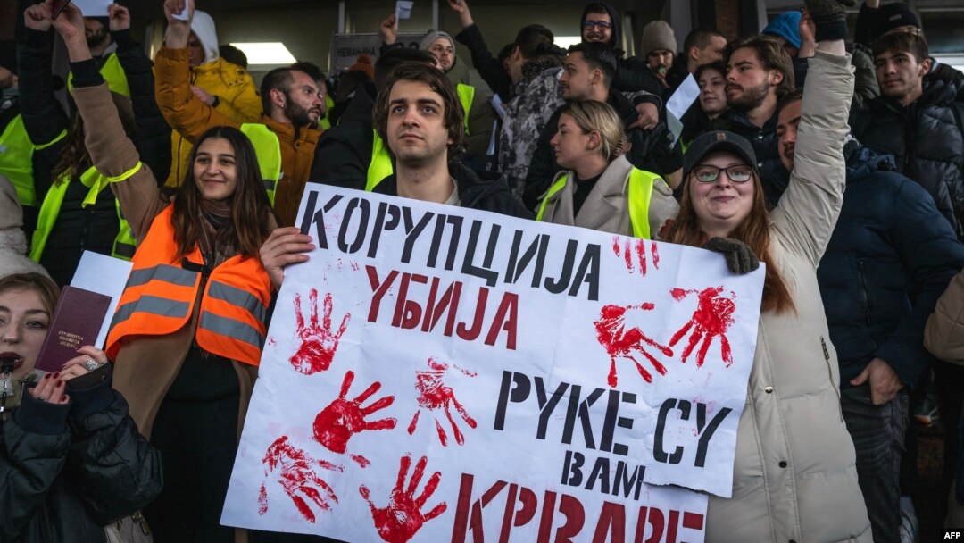 A Belgrade student hold a placard reading "Corruption kills, you have blood on your hands" as protesters gather outside the Supreme Public Prosecutor's Office on December 25 to demand accountability for the deadly rooftop collapse at the Novi Sad train station.