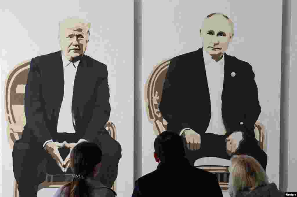 Visitors stand in front of a a fragment of an artwork depicting U.S. President Donald Trump and Russian President Vladimir Putin at an art gallery in Livadia Park in Yalta, Crimea.