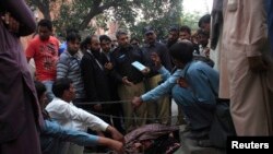 Police collect evidence near the body of Farzana Parveen, who was stoned to death by her relatives in Lahore on May 27.