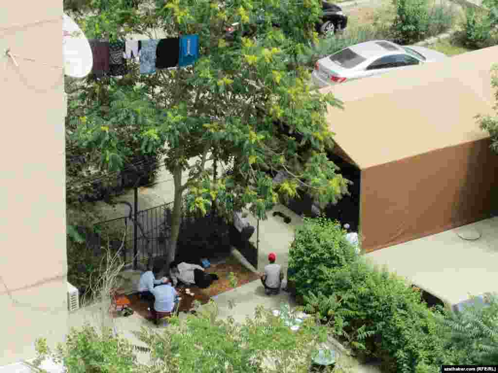 Paýtagtda dikilen çadyryň golaýynda adamalar çaý içýärler.