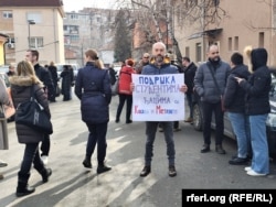 Një protestues mban një pankartë derisa proteston në shenjë mbështetjeje me protestuesit në Beograd.