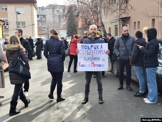 Një protestues mban një pankartë derisa proteston në shenjë mbështetjeje me protestuesit në Beograd.