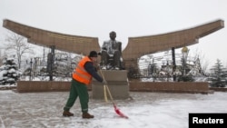 A worker removes snow in front of a statue of President Nursultan Nazarbaev in Almaty.