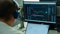 Un bărbat urmărește fluctuația cursului de schimb BTC (Bitcoin) - USDT pe una din platformele de tranzacționare a criptovalutelor. Imagine ilustrativă