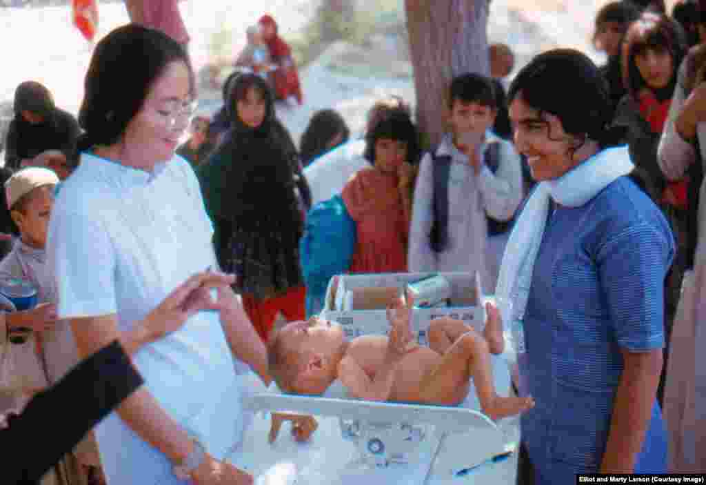 A child being measured and weighed in a village clinic. The woman on the&nbsp;left is an American Peace Corps nurse working with an Afghan student nurse (right).