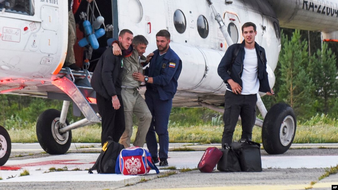 Anatoly Prytkov, one of the pilots of the An-28, is helped by his colleagues to exit a helicopter that was also carrying the other surviving passengers at an airport outside Tomsk.