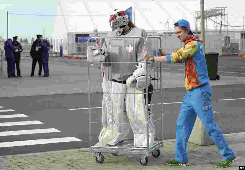 A volunteer transports Switzerland&#39;s women ice-hockey team goalkeeper Florence Schelling to a practice session.