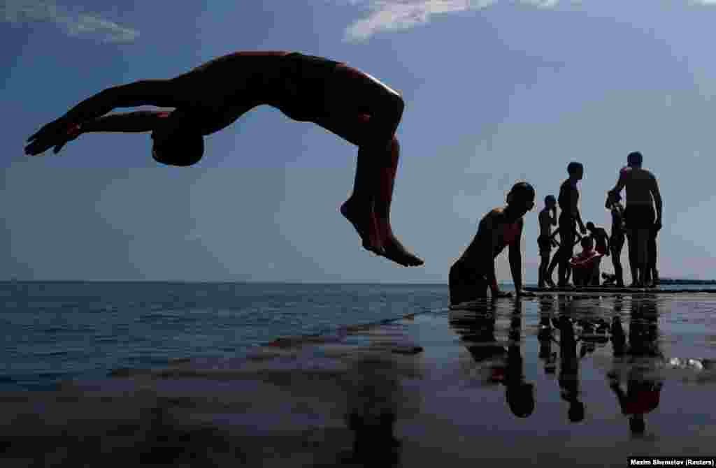 A boy jumps into the Black Sea from a pier in central Sochi, Russia, on June 30. (Reuters/Dmitry Serebryakov)