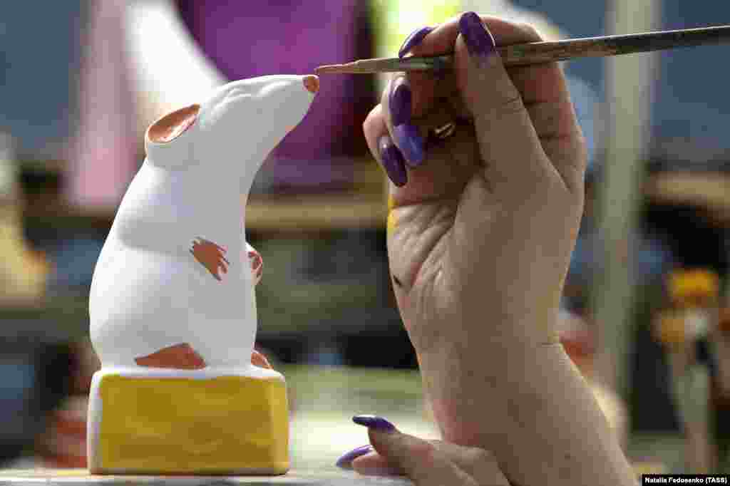 A ceramic rat gets his snout dabbed with paint.