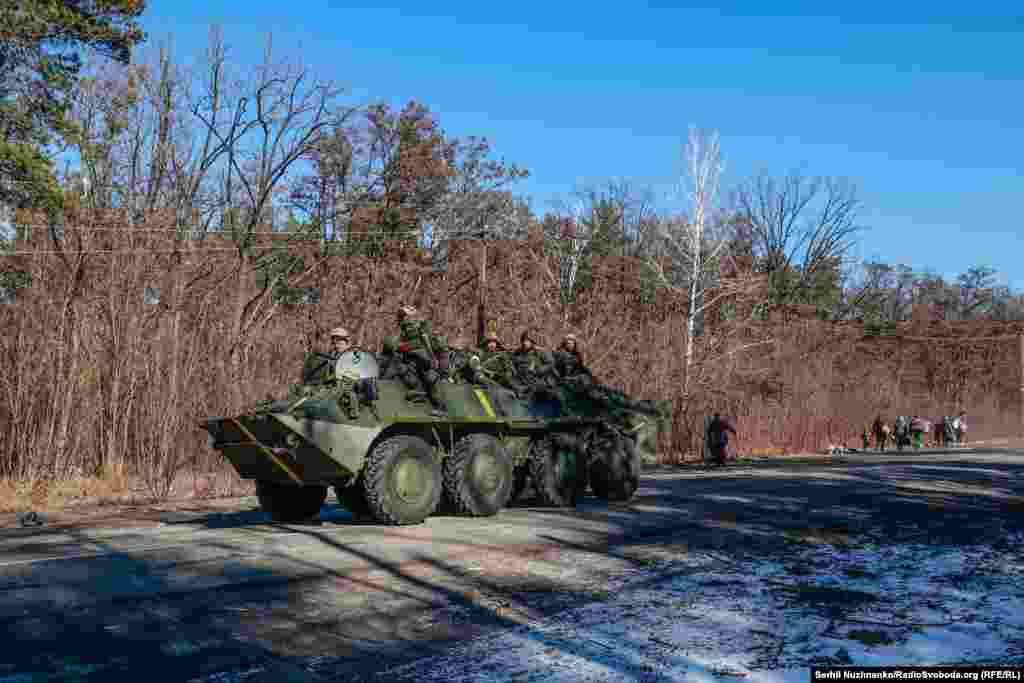 Українські військові рухаються дорогою в бік окупованого Демидіва, позаду в протилежний бік ідуть цивільні, які пішки тікають від російських загарбників, 10 березня 2022 року