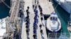 Мигранти придружувани од италијанската полиција во пристаништето Шенѓин, северозападна Албанија, на 28 јануари 2025 година.