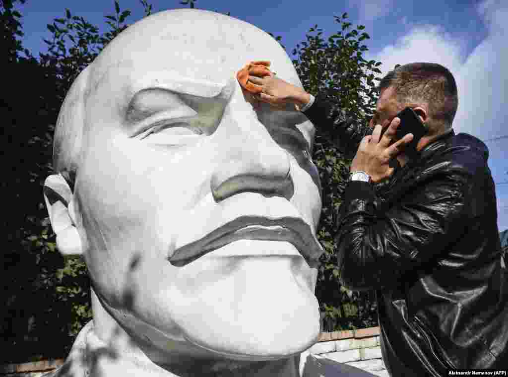 A staff member of a local branch of the Russian Communist Party washes a huge monument to Soviet founder Vladimir Lenin in front the party&#39;s local office in Novosibirsk. (AFP/Aleksandr Nemenov)