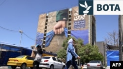 Qytetarët në Teheran duke kaluar pranë një bilbordi kushtuar Ngushticës së Hormuzit, ku shkruan "Gjithmonë në duart e Iranit". 25 maj 2026. 