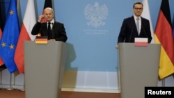 German Chancellor Olaf Scholz (left) and Polish Prime Minister Mateusz Morawiecki talk to reporters in Warsaw on December 12. 