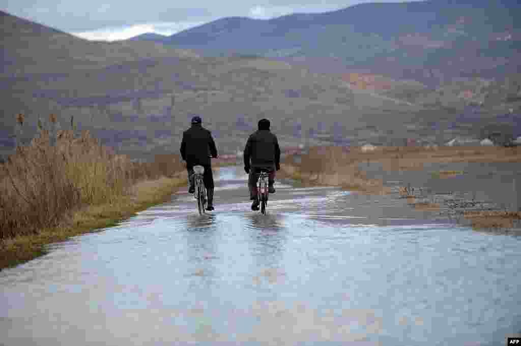 Two men ride bicycles on a flooded road in the village of Cesinovo near the town of Stip, Macedonia. (AFP/Robert Atanasovski)