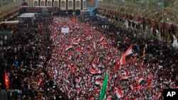 Followers of Shiite cleric Moqtada Al Sadr chant slogans against corruption, the U.S. and Israel during demonstrations while gathering between the holy shrines of Imam Hussein and Imam Abbas on the Arbaeen Shiite festival in Karbala, Iraq, Saturday, Oct. 