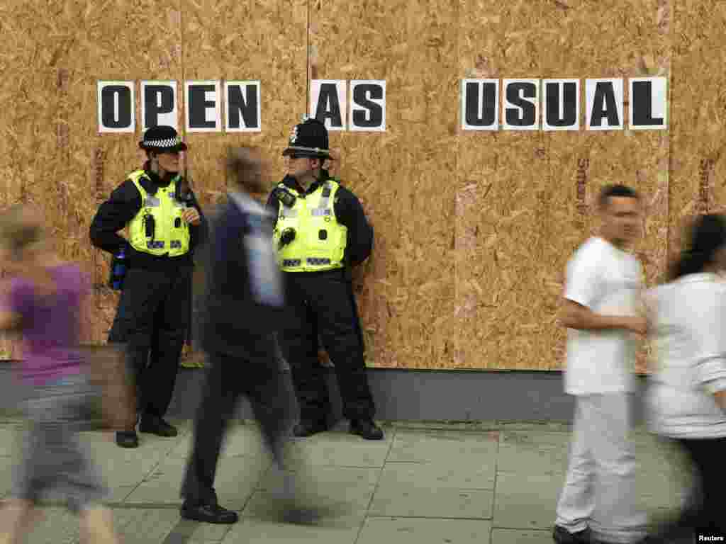 Police officers patrol outside a boarded-up shop in Streatham, south London, on August 10. Photo by Stefan Wermuth for Reuters