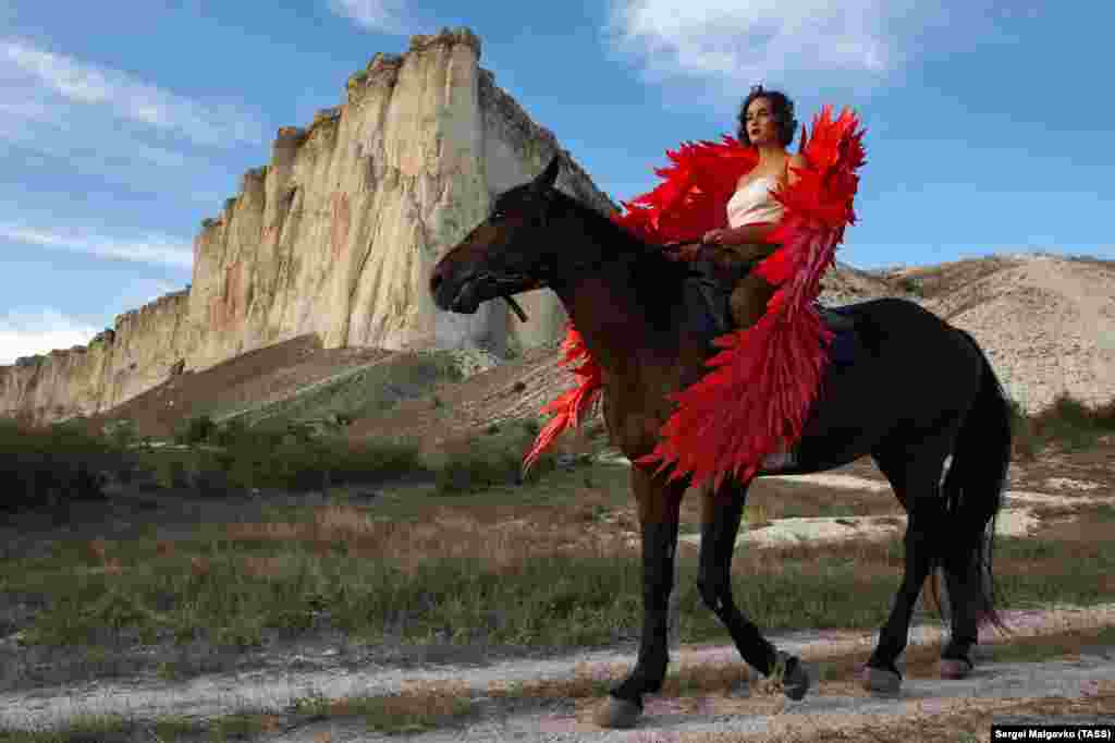 A model wearing a creation rides a horse during an outdoor fashion show for collections by Crimean designers near Ak-Kaya Rock in the Belgorsk district of Crimea during Crimean Fashion Week. (TASS/Sergei Malgavko)