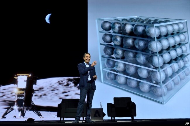 جف کونز در کنار تصویری از محموله‌ای که بعداً به‌عنوان نخستین اثر هنری به ماه فرستاده شد