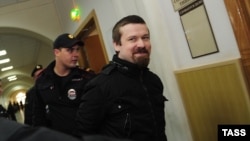 Opposition activist Leonid Razvozzhayev is escorted by a Russian police guard to his September 30 appearance in the Basman District Court.