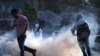 VENEZUELA -- Venezuelans run away from tear gas during scuffles with security forces in Caracas, April 30, 2019