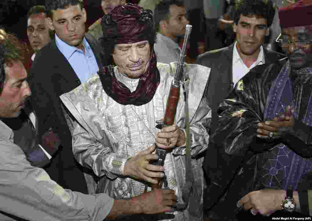Former Libyan leader Muammar Qaddafi holds a rifle presented to him as a gift by tribal leaders in October 2009.