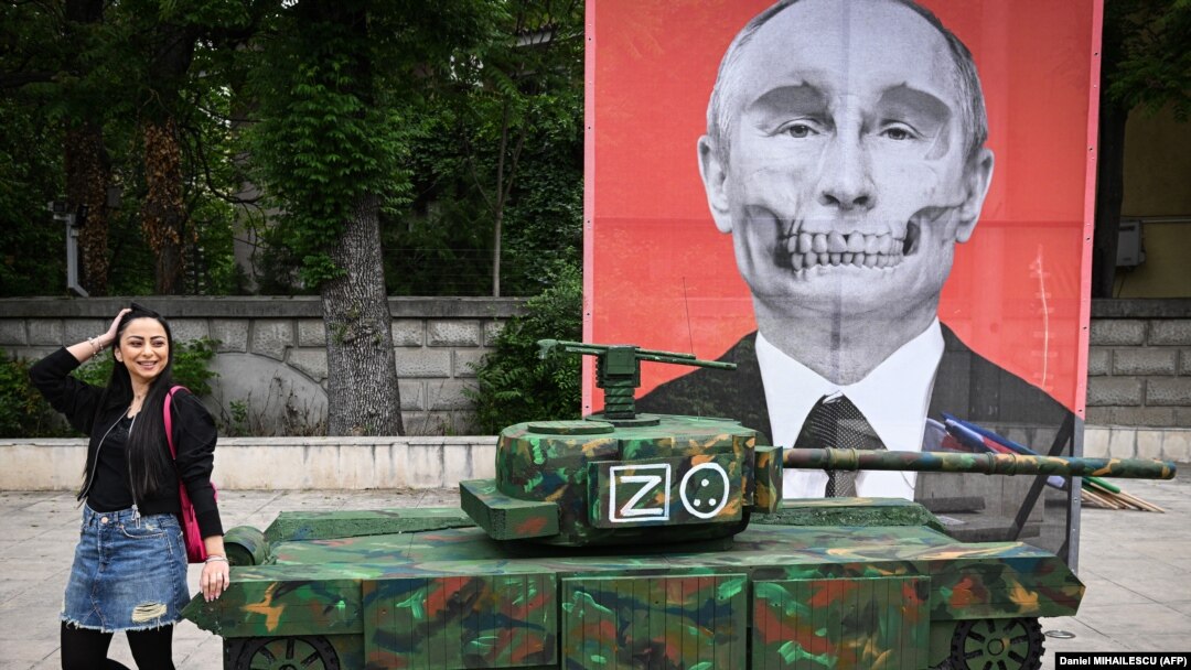 O tânără din ONG-ul „ARESEL” pozează lângă macheta unui tanc rusesc și un portret al lui Putin, 16 mai 2022. Zeci de activiști romi au protestat la Ambasada Rusiei din București față de o relatare a presei, că romii ucraineni ar fi furat un tanc rusesc.