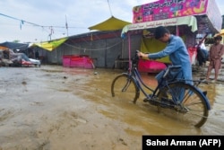 A villager pushes a bike along a road after a flash flood in Charikar, Parwan Province, in August 2020.